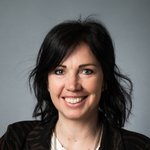 Unterpustertal/Gadertal Porträt einer lächelnden Frau mit dunklen Haaren vor grauem Hintergrund