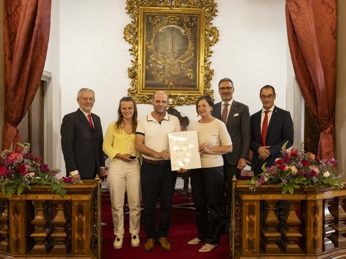Premio Economia 2026: premiate 8 aziende associate lvh.apa Sei persone in una stanza con tende rosse e un quadro dorato appeso alla parete