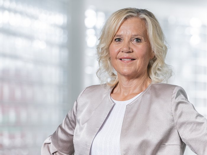 Starke Stimme für das Handwerk in Südtirols Gemeindestuben Ältere Frau mit hellblondem Haar in silberner Jacke lächelnd vor unscharfem Hintergrund