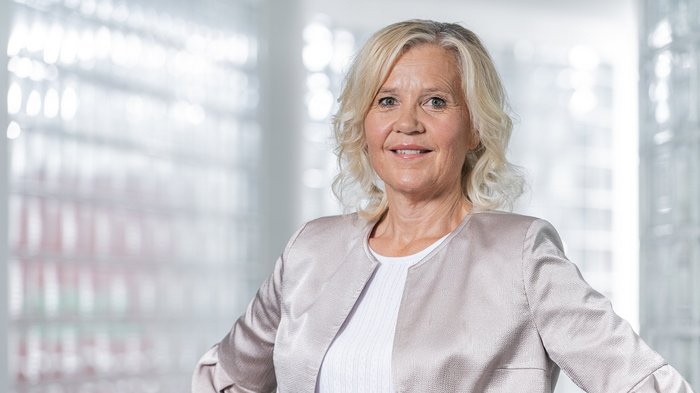 Una voce forte per l’artigianato nelle sale consiliari altoatesine Donna anziana con capelli biondi chiari e giacca argento che sorride davanti a sfondo sfocato