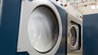 Textilreiniger Industriewaschmaschinen in Betrieb mit Sicht auf die rotierenden Trommeln