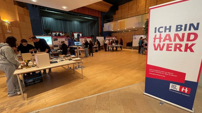 Mittelschüler mittendrin, in der Welt der praktischen Berufe Handwerksmesse mit Ständen und Menschen in einer großen Halle