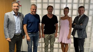 News Fünf Personen stehen nebeneinander vor einer Glaswand in einem Büro