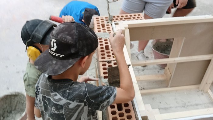 KidsAcademy 2025: Ein Sommer voller Handwerk und Kreativität Kinder lernen Mauern bauen mit Ziegeln und Mörtel unter Anleitung