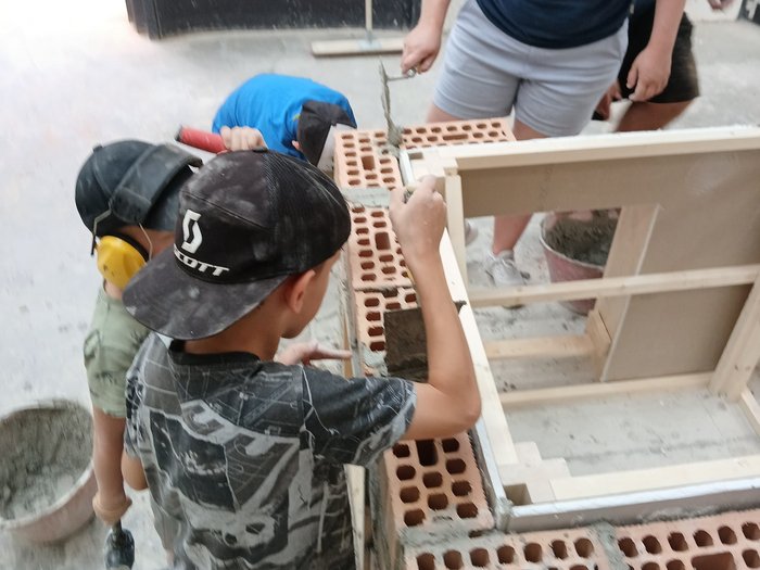 KidsAcademy 2025: Ein Sommer voller Handwerk und Kreativität Kinder lernen Mauern bauen mit Ziegeln und Mörtel unter Anleitung