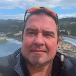 Burggrafenamt Porträt eines Mannes mit Sonnenbrille auf dem Kopf vor einer Küstenlandschaft