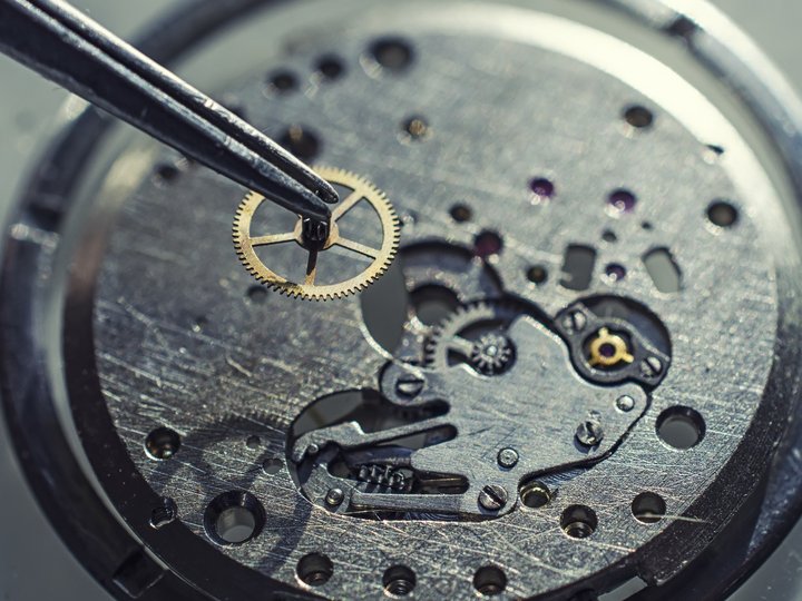 Orologiai Pinzetta tiene un piccolo ingranaggio sopra meccanismo di orologio