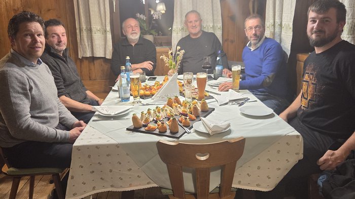 lvh zu Besuch im Berufsbildungszentrum „Emma Hellenstainer“ Sechs Männer sitzen an einem Tisch mit Snacks und Getränken in einem Holzraum