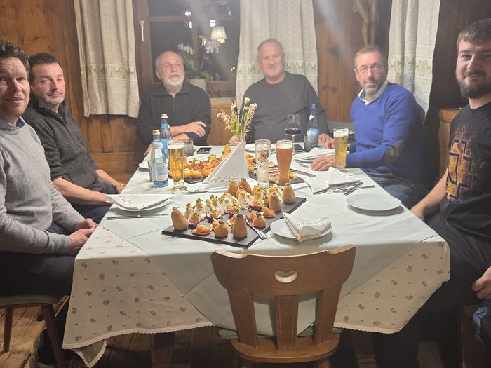 Austausch, Kontinuität und Blick nach vorn Sechs Männer sitzen an einem Tisch mit Snacks und Getränken in einem Holzraum