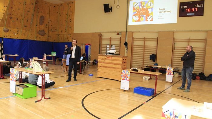 Kreative Spielideen: Preisverleihung für "Clever gebaut" Präsentation in Turnhalle mit Sprecher und Zuhörern