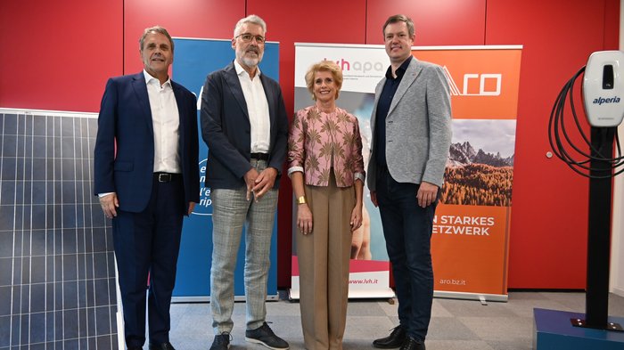 Artigianato da vicino: lo SkillsDay genera entusiasmo in Val d'Ega Quattro persone in piedi davanti a sfondo rosso con pannelli solari e striscioni