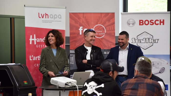 Obiettivo puntato sulle competizioni e sulle innovazioni giuridiche Tre persone sorridenti davanti a banner pubblicitari durante un evento