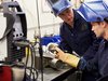 Home Due saldatori in abbigliamento protettivo lavorano insieme su tubo metallico