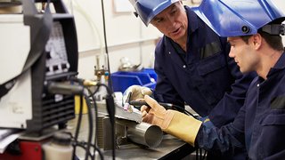 News Zwei Schweißer in Schutzkleidung arbeiten gemeinsam an Metallrohr