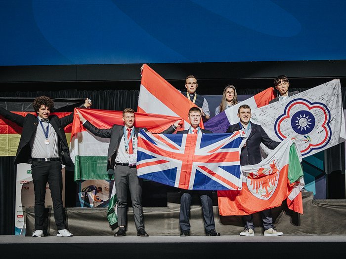 WorldSkills in Bozen: Bronzemedaille und Medallion for Excellence für zwei Südtiroler Siegerteam auf Bühne mit verschiedenen Nationalflaggen bei Preisverleihung