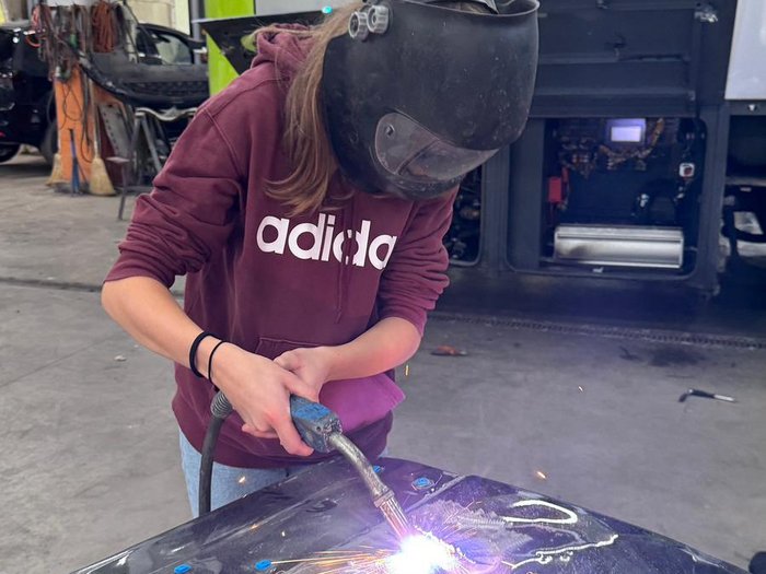 Berufsinformationskampagne in Deutschnofen und Welschnofen Person mit Schweißhelm, die in einer Werkstatt Metallteile schweißt