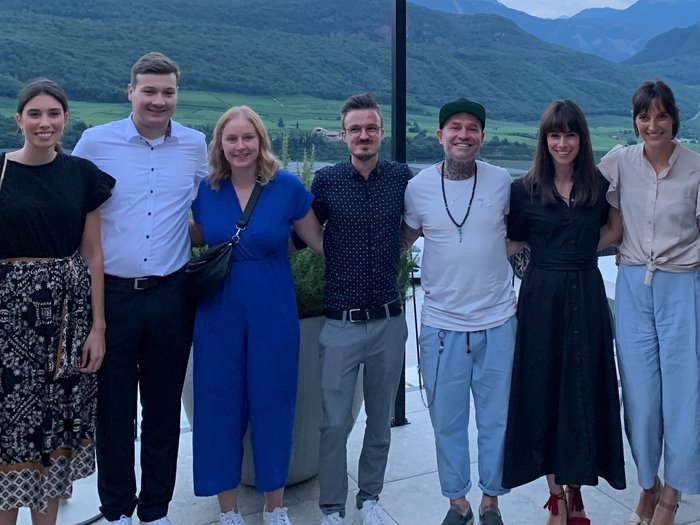 Sommercocktail der Jungen Wirtschaft Sieben Personen stehen Arm in Arm vor einer Berglandschaft