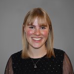 Das lvh-Team Porträt einer lächelnden Frau mit blonden Haaren und schwarzem Oberteil vor grauem Hintergrund