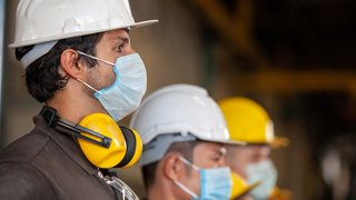 News Bauarbeiter mit Schutzhelmen und Mundschutz stehen nebeneinander