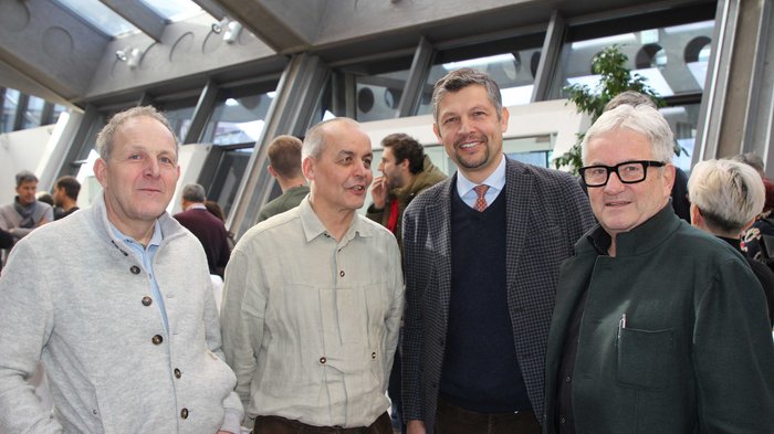Holzbaukongress: Ein großer Erfolg Vier Männer in einem hellen Raum bei einer Veranstaltung im Gespräch