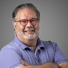 Text Element Lächelnder Mann mit roter Brille und violettem Polohemd vor grauem Hintergrund