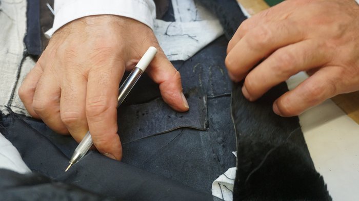 Pellicciai Mani di un sarto che preparano e segnano il tessuto per una cucitura