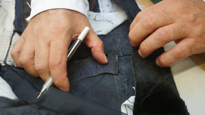 Pellicciai Mani di un sarto che preparano e segnano il tessuto per una cucitura