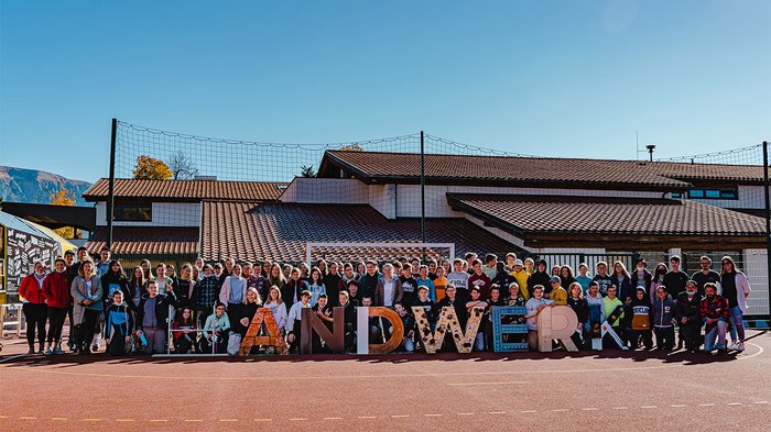 Junghandwerker Ritten besuchen Mittelschüler Große Gruppe von Kindern und Erwachsenen vor einem Schulgebäude mit dem Schriftzug HANDWERK