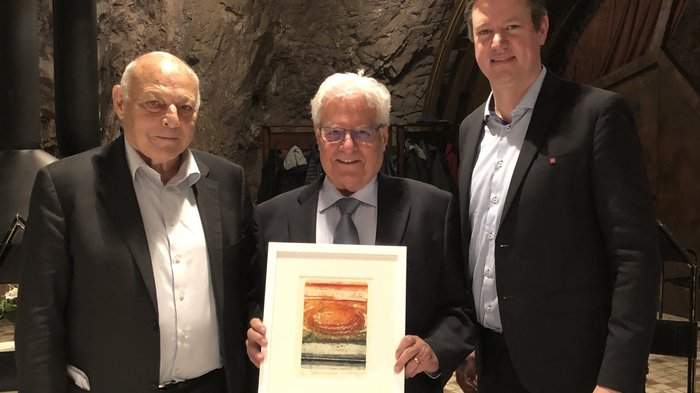 Bilaterale Körperschaft: verdiente Akteure geehrt Drei Männer in Anzügen, einer hält ein gerahmtes Bild vor einer Felswand