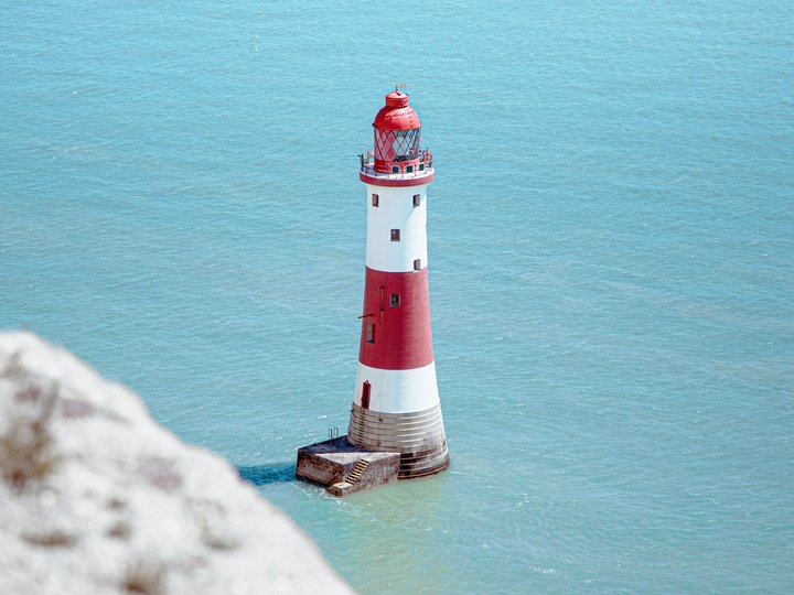 Incentivi innovativi e allo sviluppo di prodotti Faro con strisce rosse e bianche nel mare calmo blu