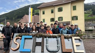 News Gruppe von Jugendlichen hinter großem Schriftzug SCRULF vor Haus und Bergen