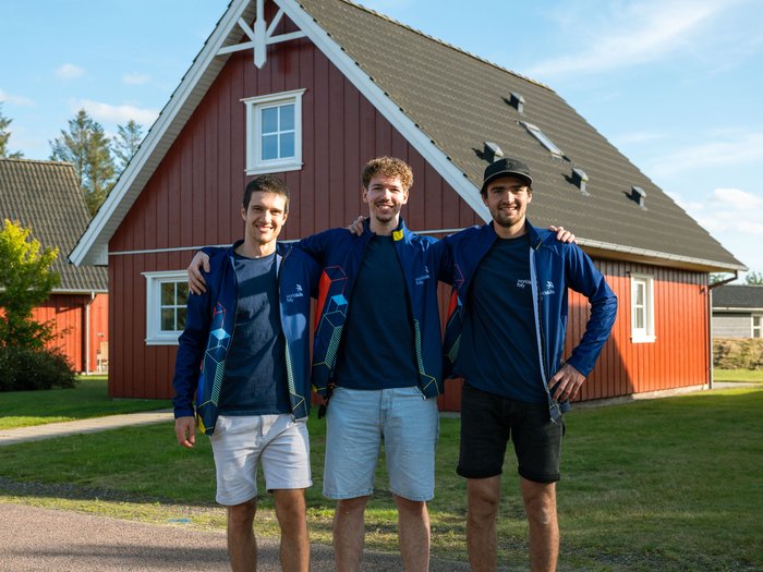 EuroSkills 2025: Südtirols Teilnehmer starten in den Wettbewerb Drei junge Männer mit blauen Jacken posieren vor einem roten Haus im Freien