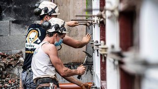 News Zwei Bauarbeiter mit Helmen bei Montagearbeiten auf der Baustelle