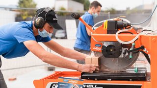 News Arbeiter schneidet Ziegelsteine mit einer elektrischen Schneidemaschine