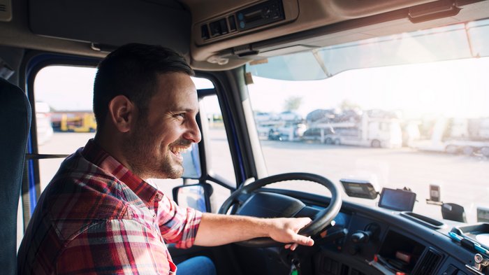 Förderung für Ausbildung junger Lkw-Fahrer Lächelnder Mann sitzt am Steuer eines Lastwagens
