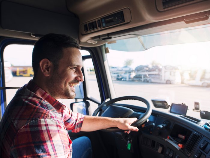 Sostegno per la formazione dei giovani autisti Uomo sorridente al volante di un camion