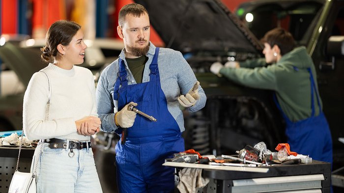 I falegnami puntano su scambio, innovazione e qualità Meccanico spiega riparazione auto a cliente officina con cofano motore aperto