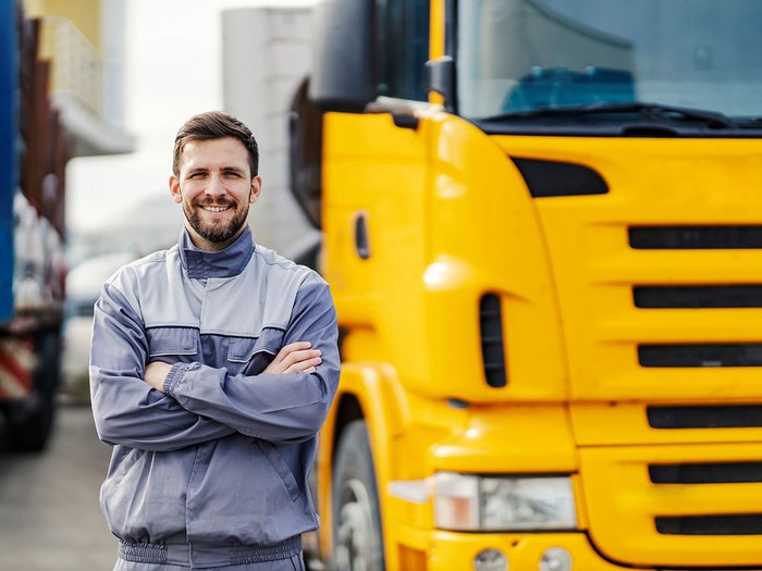 WIFO-Wirtschaftsbarometer Herbst 2024 Lächelnder LKW-Fahrer in grauer Arbeitskleidung vor gelbem LKW