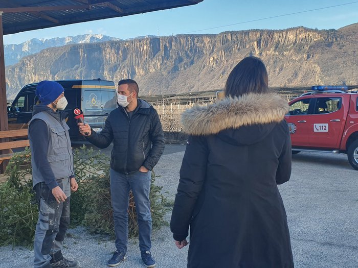 Aktivitäten der Hafner/innen im lvh Reporter interviewt Mann vor Bergen mit Feuerwehrauto im Hintergrund