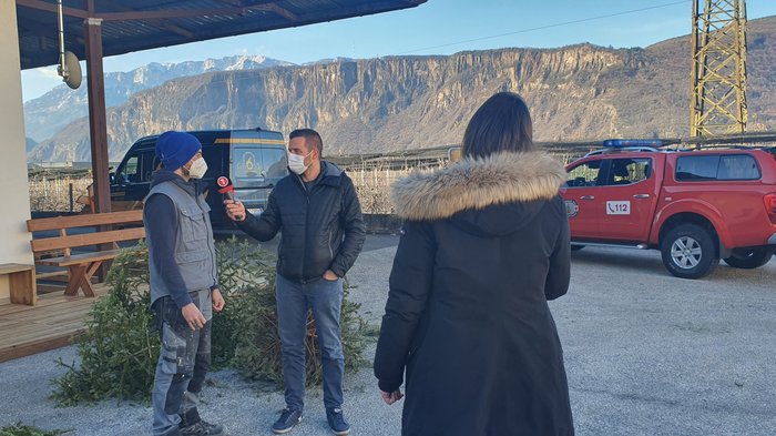 Aktivitäten der Hafner/innen im lvh Reporter interviewt Mann vor Bergen mit Feuerwehrauto im Hintergrund