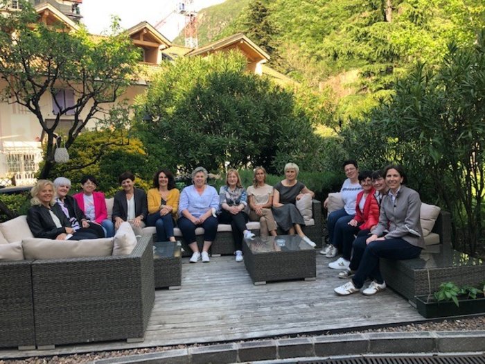 Le Donne nell’Artigianato pensano al futuro Gruppo di donne sedute su mobili da giardino all'aperto vicino a alberi e montagne