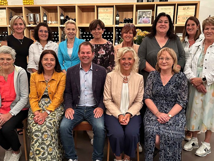 La presidente di Garfidi incontra le donne nell’artigianato Foto di gruppo di 14 persone di fronte a scaffali di vino in interno