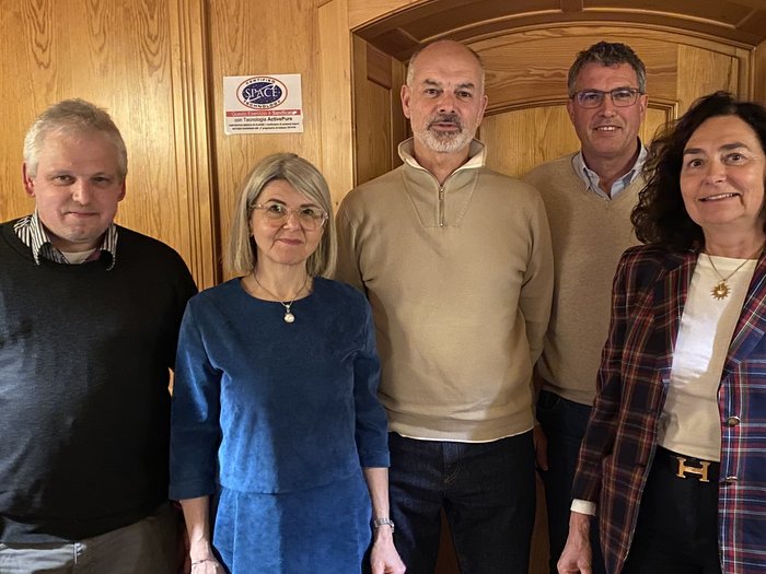 Riunione del gruppo comunale di lvh.apa a Bronzolo: bilancio del 2024 e prospettive per le iniziative future Cinque persone stanno in piedi davanti a una parete di legno in una stanza accogliente