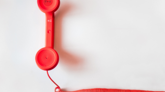 Artigianato sostenibile Ricevitore telefonico rosso con cavo arrotolato su sfondo bianco