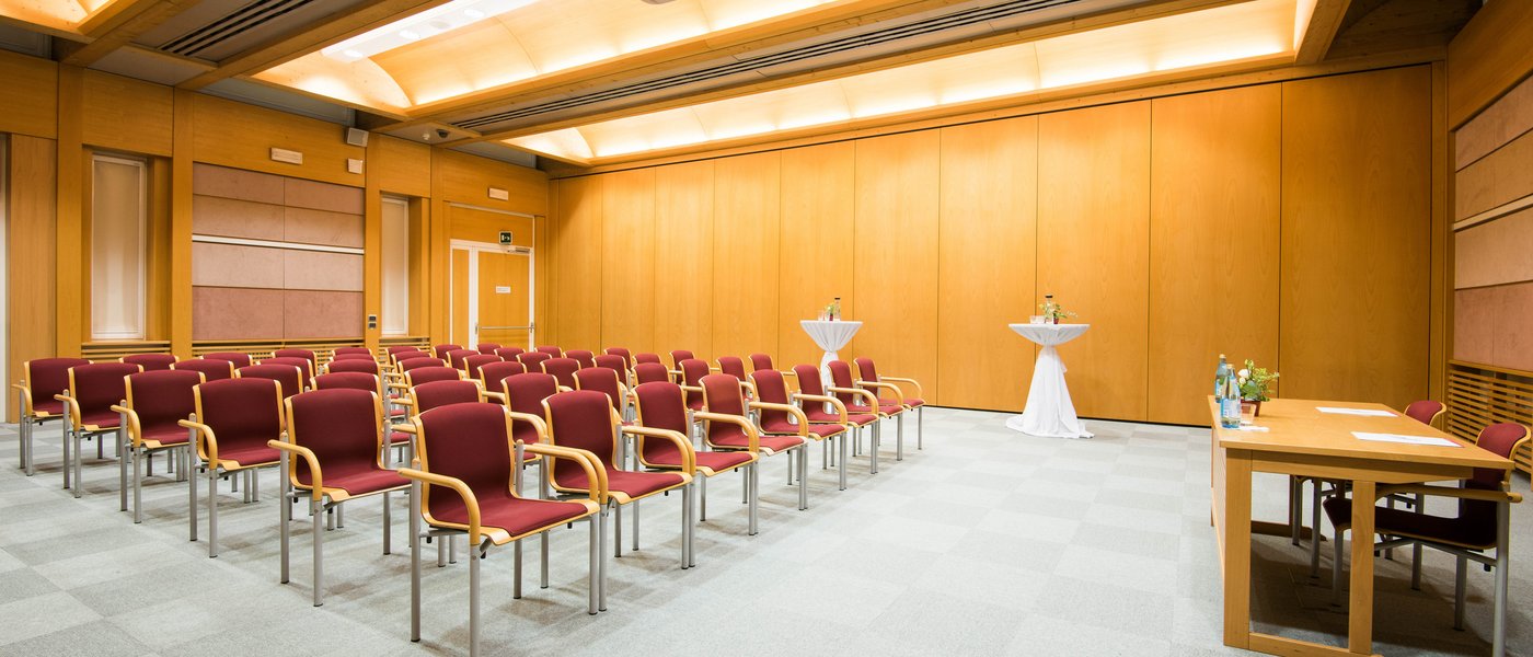 Affitto aule seminari Sala conferenze vuota con sedie, due tavoli alti e un tavolo davanti