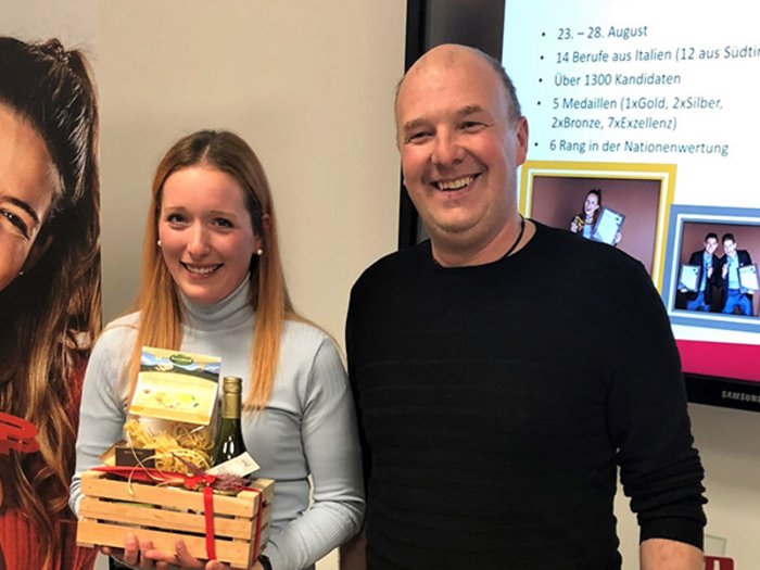 Junges Handwerk auf dem Vormarsch Zwei Personen halten Geschenkkorb vor Wand mit Infos und Fotos