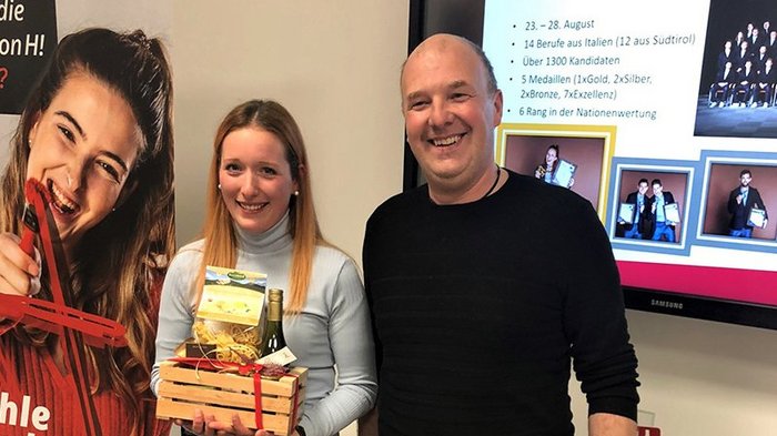 Junges Handwerk auf dem Vormarsch Zwei Personen halten Geschenkkorb vor Wand mit Infos und Fotos