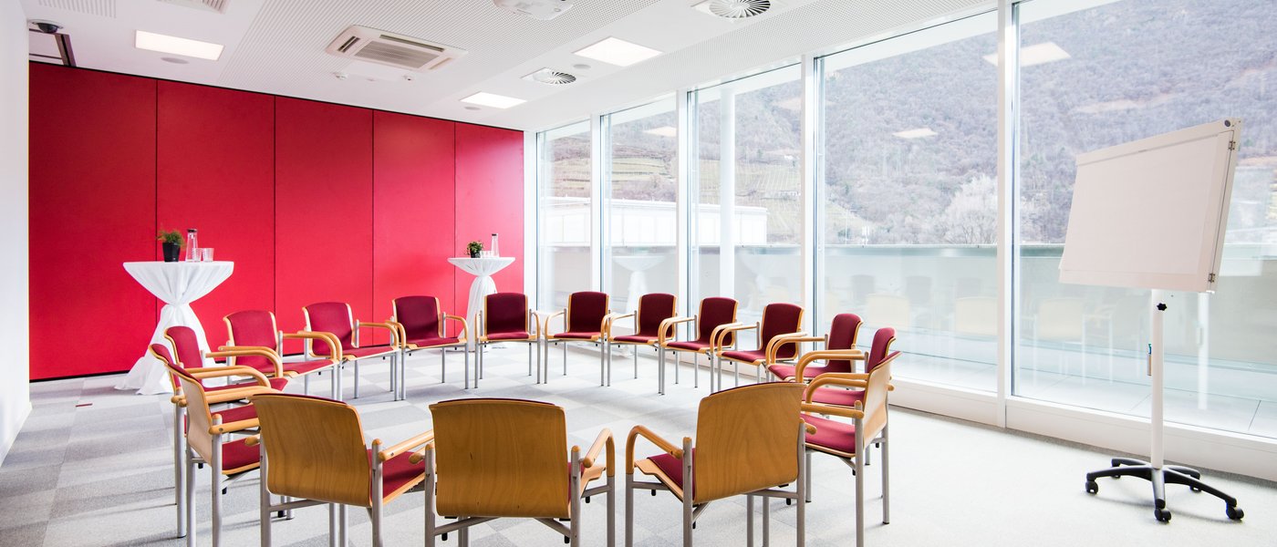 Vermietung Seminarräume Konferenzraum mit Stühlen im Kreis, Flipchart und großen Fenstern mit Bergblick