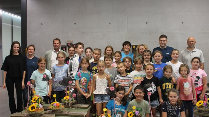 Blütenzauber und Gartenpracht: Das große Finale der KidsAcademy findet in Laimburg-Pfatten statt Gruppenfoto von Kindern mit ihren Blumenarrangements und Betreuern an der Wand