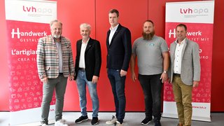 News Fünf Männer stehen vor roten Bannern des Wirtschaftsverbands Handwerk und Dienstleister